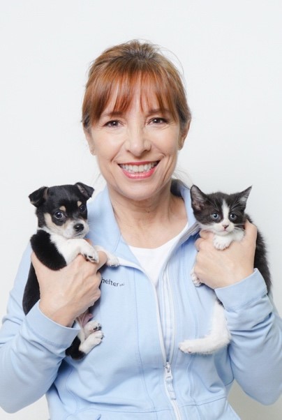 Bio photo of Dr. Sara Pizano, smiling in a pale blue warmup, holding two kittens